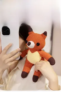 Detail of a handmade crochet fox plush toy with soft orange yarn and brown accents