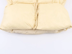 Détail d'un manteau d'hiver jaune clair avec taille à cordon et texture lisse