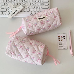 Close-up of pink quilted pencil cases with floral pattern and ribbon puller on desk