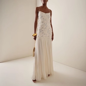 Elegante abito lungo bianco in pizzo floreale con gonna a pieghe per donna in studio