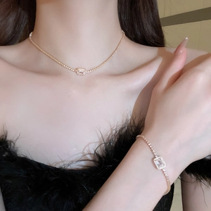 Close-up of rose gold necklace and bracelet set with rectangular zircon on a model