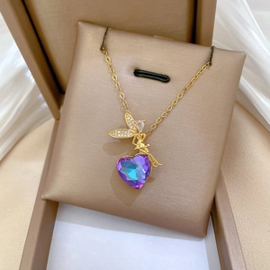 Close-up of gold angel necklace with purple heart crystal on silk background