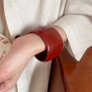Close-up of a wide red resin bangle worn on wrist with vintage aesthetic styling