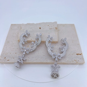 Detailed close-up of luxury silver floral earrings with sparkling zircons and bell pendants