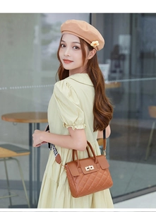Detail of caramel quilted leather handbag with gold lock and branded shoulder strap
