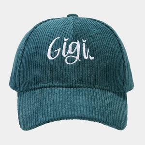 Close-up of white Gigi embroidery on dark green corduroy baseball cap texture