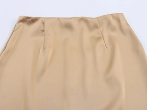 Detail of champagne satin skirt waistline featuring smooth glossy texture and sewing