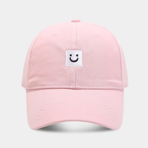 Détail d'une casquette de baseball en coton rose avec patch brodé de visage souriant