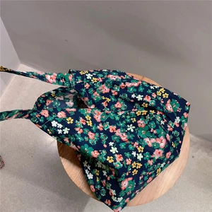 Floral cotton tote bag detail on wooden stool showing vintage navy pattern and fabric texture