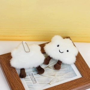 Cute white plush cloud keychains with smiling faces on a warm wooden background