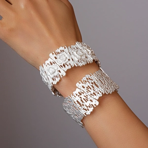 Detailed shot of matte silver bracelets featuring embossed rose and irregular hollow design