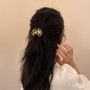 Rear view of model wearing a gold metal hair claw with white pearl on elegant hairstyle
