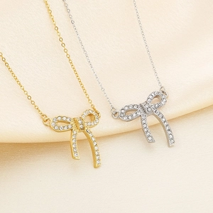 Detail of gold and silver bow necklaces with sparkling rhinestones on silk fabric