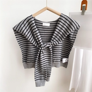 Close-up of grey knitted shawl with black stripes featuring a front knot and neck label