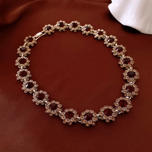 Detail of flower-shaped links with deep red gemstones on a vintage gold necklace