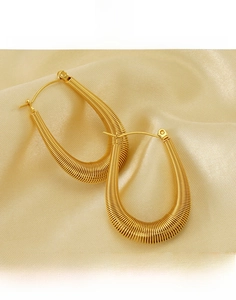 Detailed macro of gold-plated U-shaped titanium hoop earrings with spiral thread texture