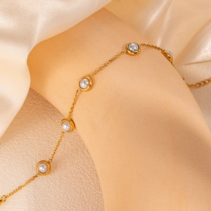 Close-up of elegant gold chain bracelet with white pearls on a soft silk background