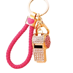 Golden whistle keychain with pink rhinestones and a braided wrist strap on white background