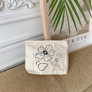 Detailed embroidery of floral patterns on a premium cream canvas cosmetic storage bag