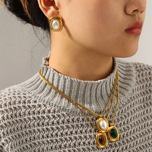 Close-up of vintage stainless steel necklaces with tiger eye and pearl earrings on model