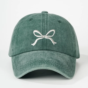 Close-up of white bow embroidery on a vintage washed green cotton baseball cap