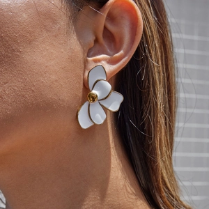 Close-up of white flower earring with gold-plated edges worn on model's ear