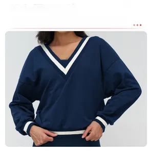 Detail of V-neck collar and black-white striped ribbed cuffs on navy blue sweatshirt