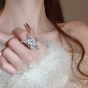 Close-up of a silver butterfly ring with sparkling zircon stones worn on finger