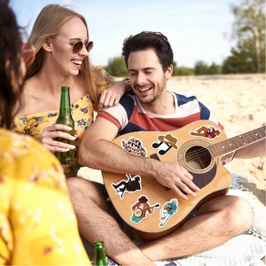 Acoustic guitar decorated with country music cowboy stickers during a beach party