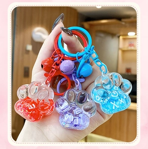 Close-up of three colorful cat paw liquid sand keychains with glitter and charms