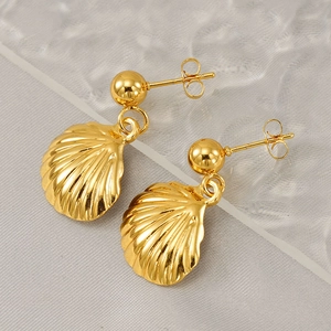 Golden shell earrings with fan-shaped texture and smooth round stud on watery glass background