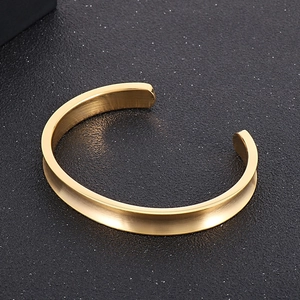 Detailed close-up of golden stainless steel open cuff bracelet with U-shaped groove design