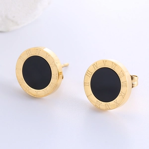 Macro view of gold stud earrings with black center and engraved Roman numerals