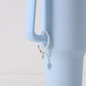 Detail of blue enamel heart charm with letter A and pearl chain on cup handle