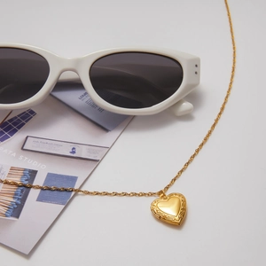 Detail of vintage heart locket necklace in gold with embossed floral edges and rope chain