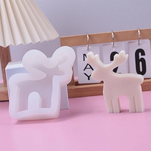 White silicone reindeer mold with finished candle product on a minimalist pink desk