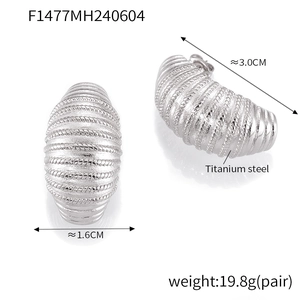 Macro detail of silver C-shaped titanium steel earrings with textured croissant layers