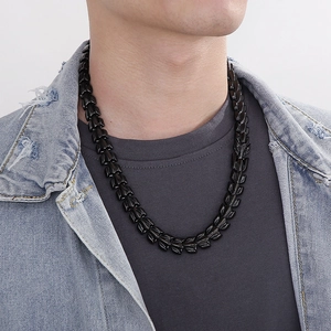 Detail of a men's punk style black stainless steel dragon bone chain necklace on a model