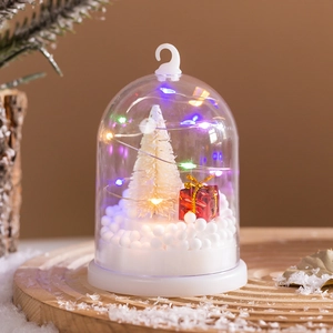 Detail of Christmas snow globe light with miniature tree, red gift box and LED lights
