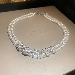 Elegant double-layer pearl necklace featuring luxury rhinestone flower pendants on beige leather