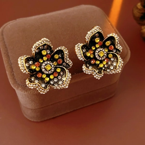 Close-up of vintage flower earrings with yellow and orange crystals on brown suede