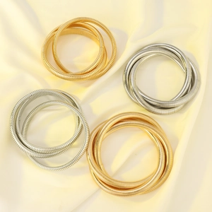 Detail of four-piece layered elastic snake bone bracelets in gold and silver finish