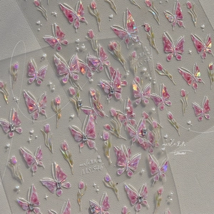 Detailed macro view of iridescent butterfly and floral nail art stickers with small rhinestones