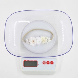 Close-up of lightweight 5g baby floral headband with fabric flowers on a digital scale