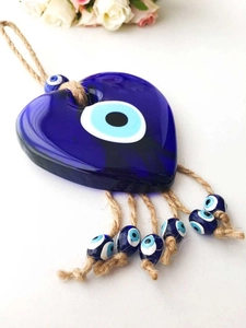 Detailed view of a glass heart evil eye pendant with natural jute rope and hanging beads