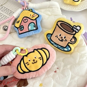 Close-up of cute cartoon plush charms with embroidery details on a quilted bag