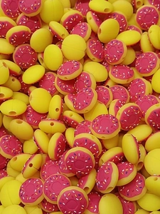 Detailed pile of yellow silicone donut beads with pink frosting for DIY cable protectors