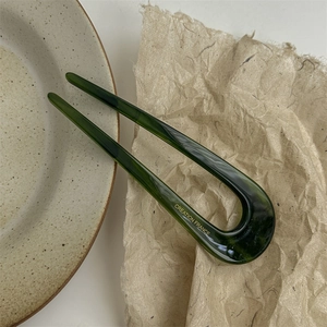 Macro shot of marble textured acetate U-shaped hair pin on ceramic and paper