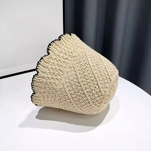 Detail of hand-woven beige straw bucket hat with black scallop trim edge texture