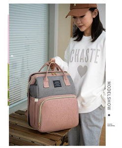 Pink and grey waterproof multi-functional diaper backpack with side pocket on a wooden bench